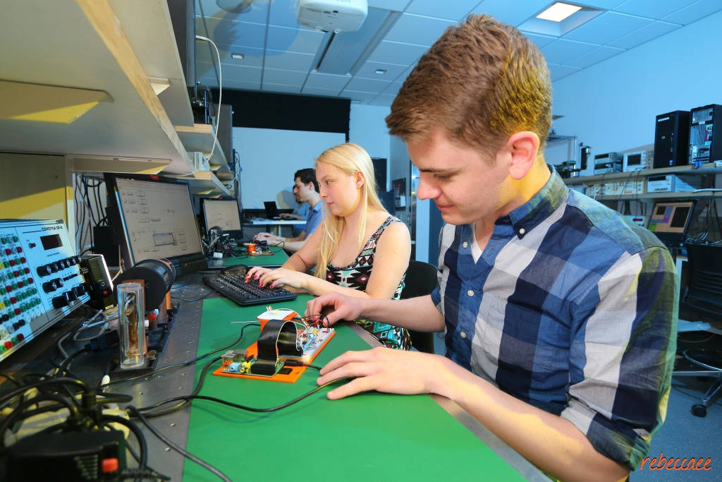 Three students working at an electronics laboratory bench